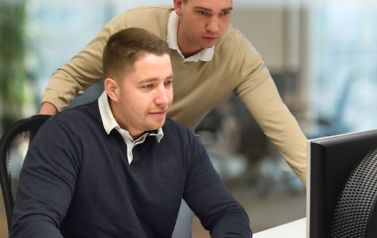 Marius und Alexander arbeiten gemeinsam am Schreibtisch am Computer