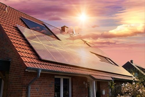 Solaranlage auf einem Häuserdach die den Sonnenuntergang reflektiert